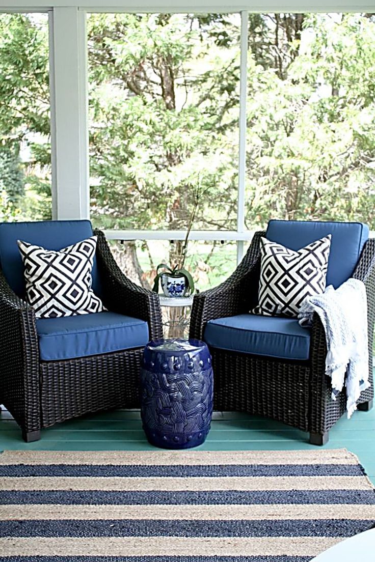 Cozy wicker chairs with blue cushions and patterned pillows on porch