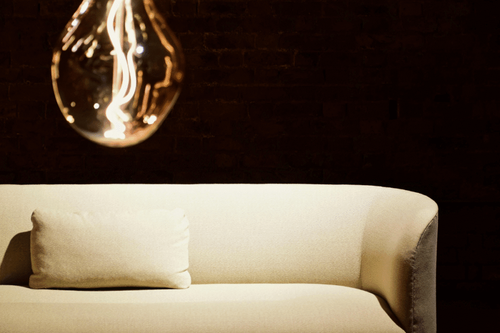 Beige sofa with matching pillow under warm light bulb