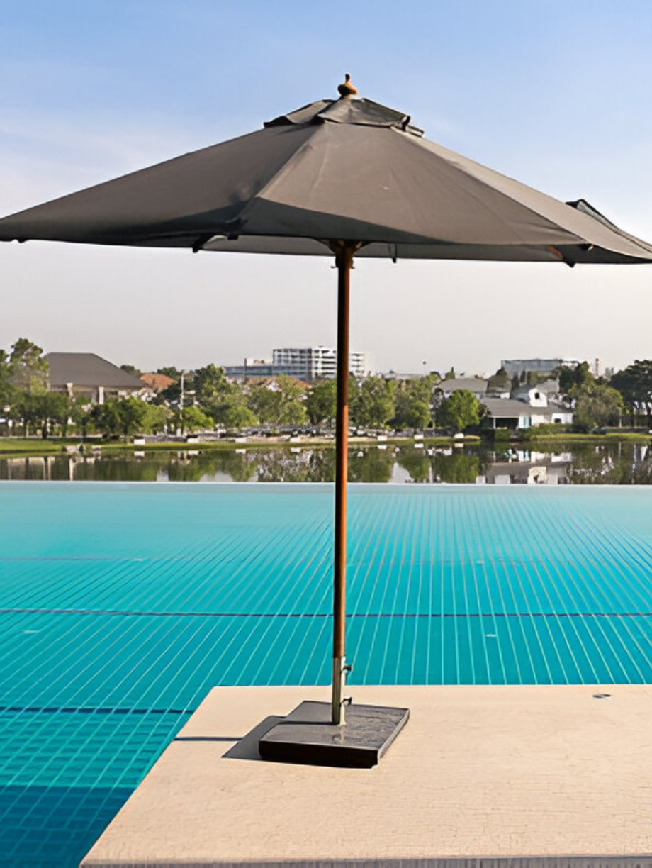 Black poolside umbrella with square base by a turquoise swimming pool