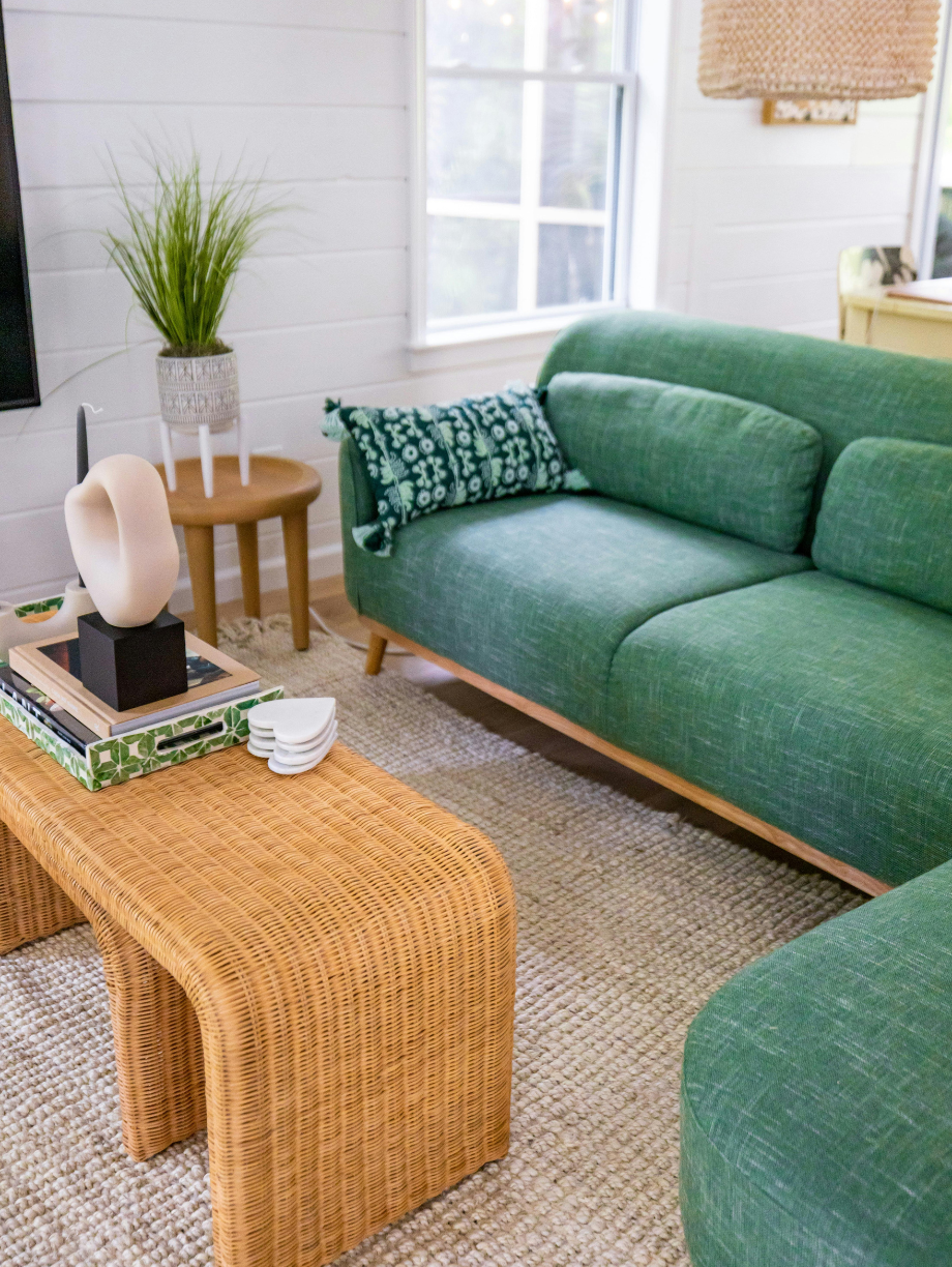 Bright living room with green sofas and a wicker coffee table