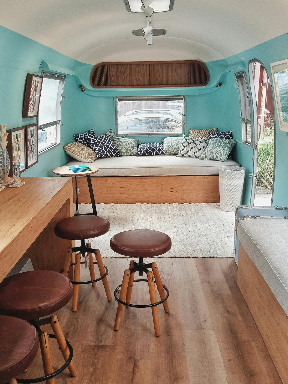 Stylish camper interior with turquoise walls, wood accents, and cozy seating