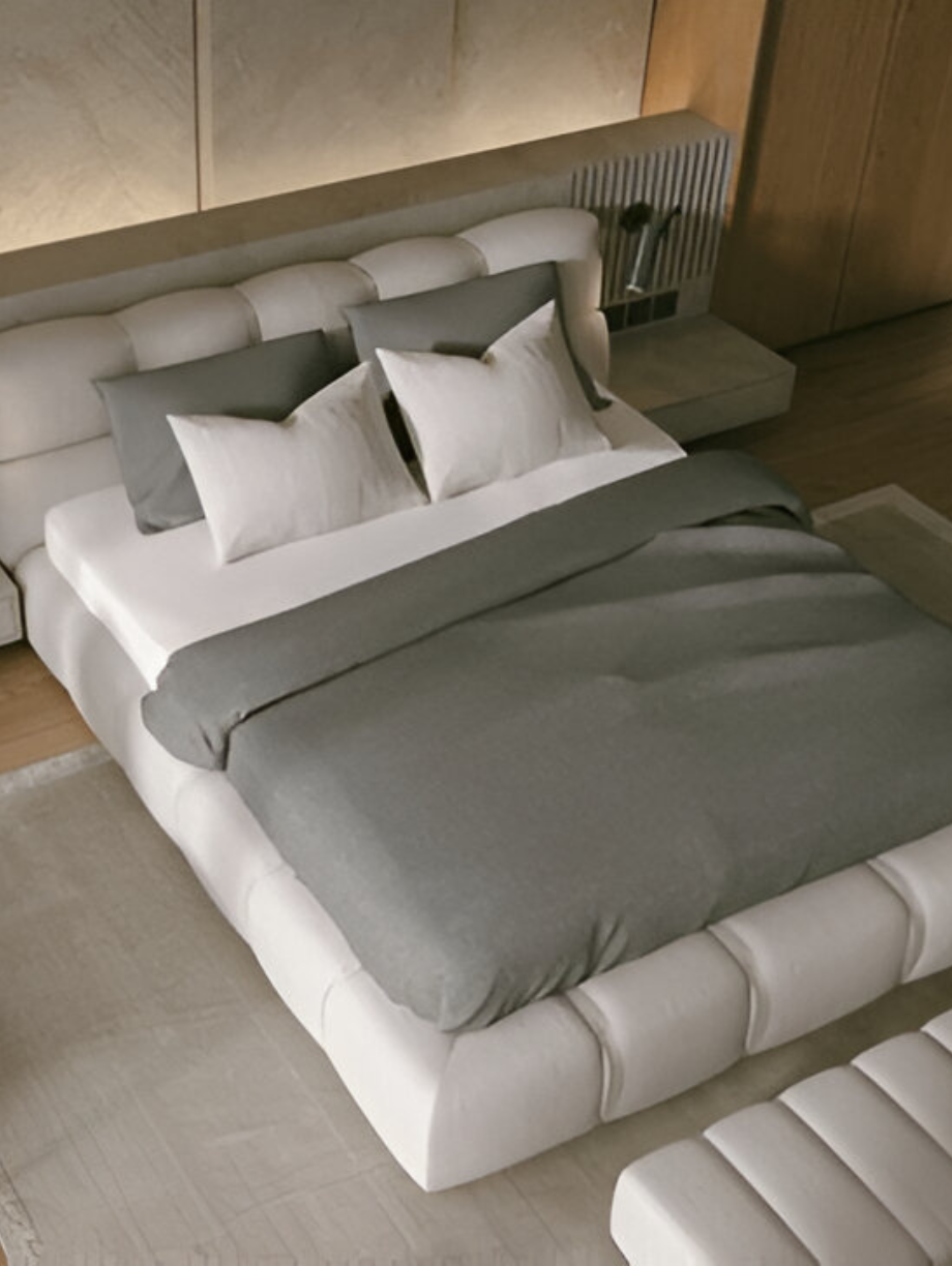 Modern minimalist bedroom with grey and white bedding on a tufted platform bed.