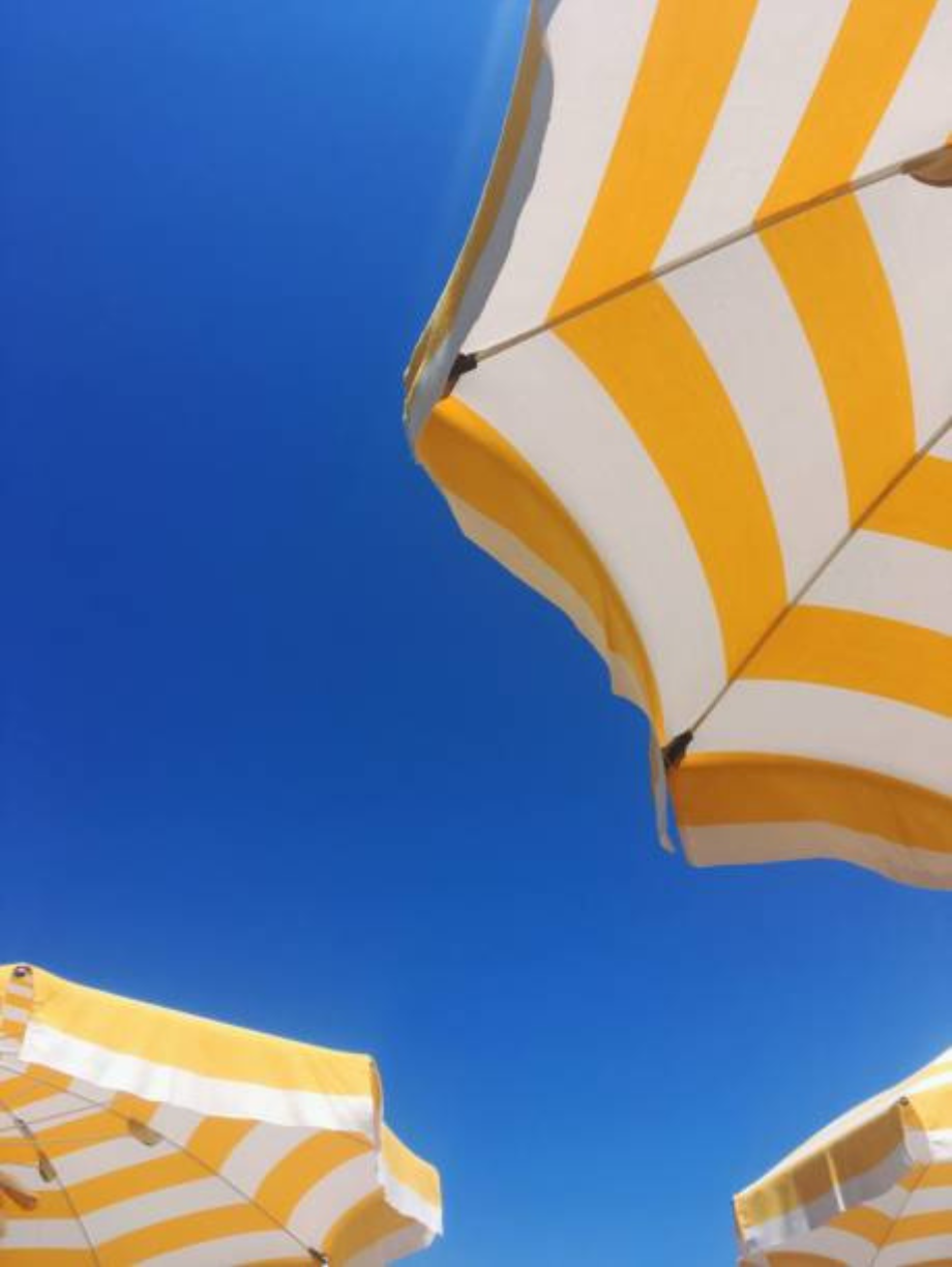 Yellow and white striped beach umbrellas against clear blue sky