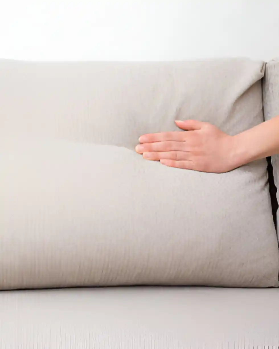 Hand pressing soft beige cushion for comfort test
