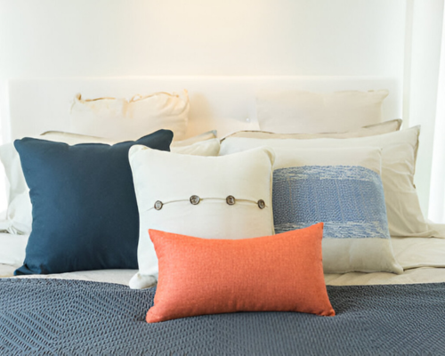Decorative pillows in blue, white, and orange on a neatly made bed