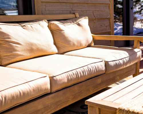 Wooden outdoor sofa with beige cushions in natural sunlight