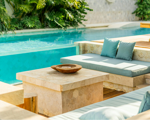 Modern outdoor seating area with stone tables and cushioned benches by a pool