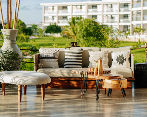 Outdoor wooden sofa with patterned cushions and wooden coffee tables on patio