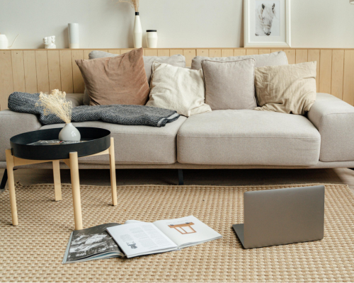 Cozy living room with beige sofa, throw pillows, and laptop on woven rug