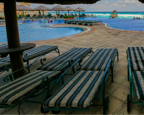 Poolside lounge chairs with ocean view at a tropical resort