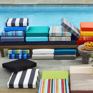Colorful outdoor cushions stacked near poolside