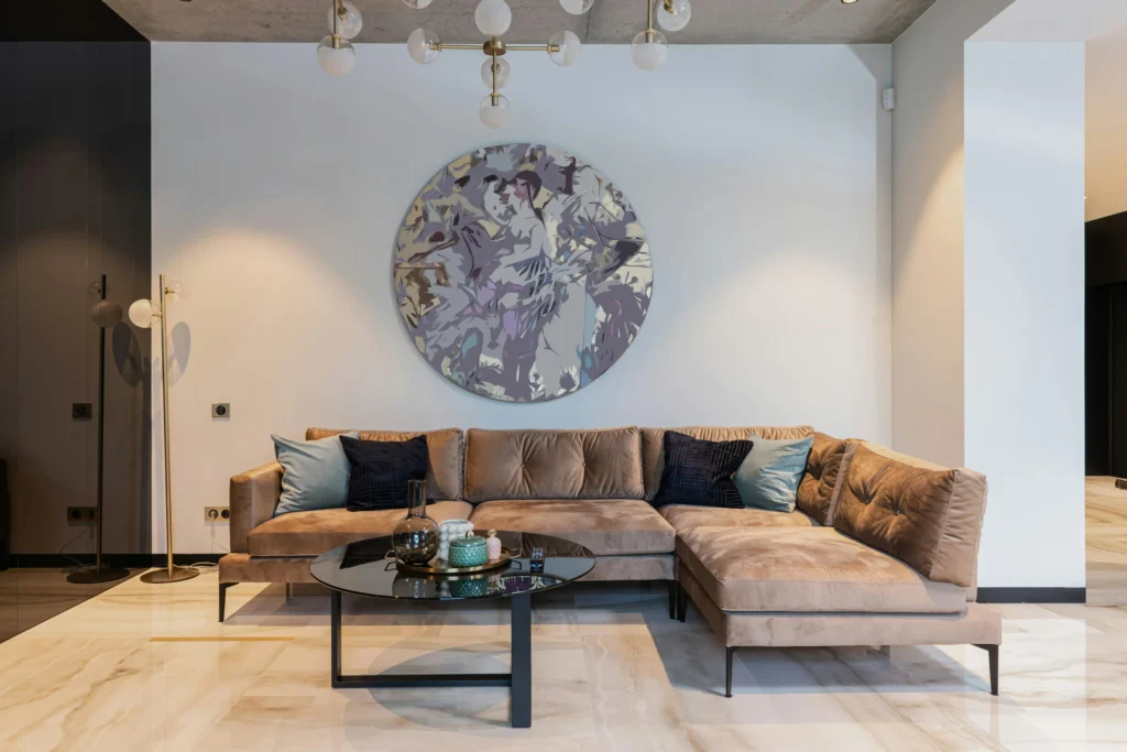 Modern living room with brown sectional sofa, round coffee table, and abstract wall art