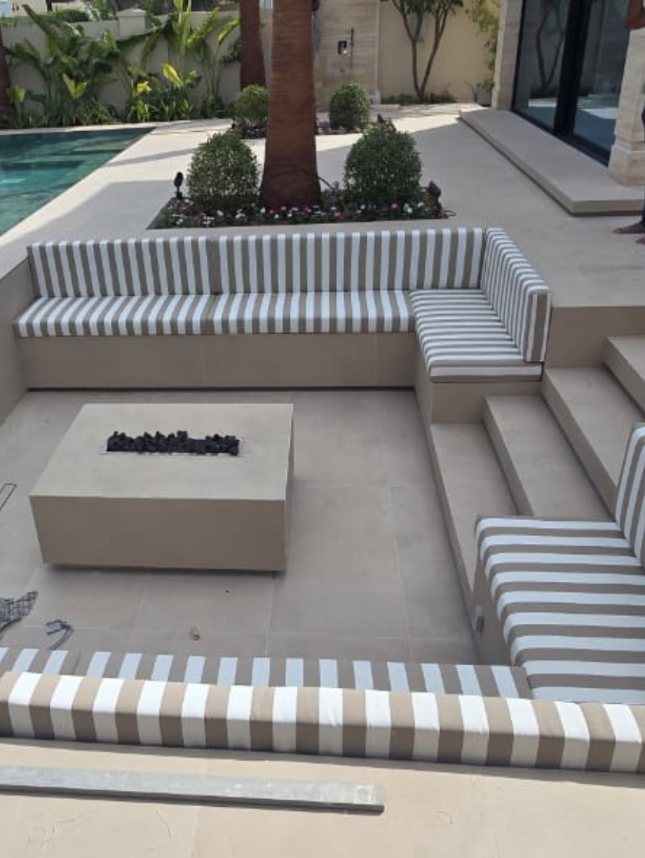 Modern outdoor L-shaped sofa with beige and white striped cushions near pool