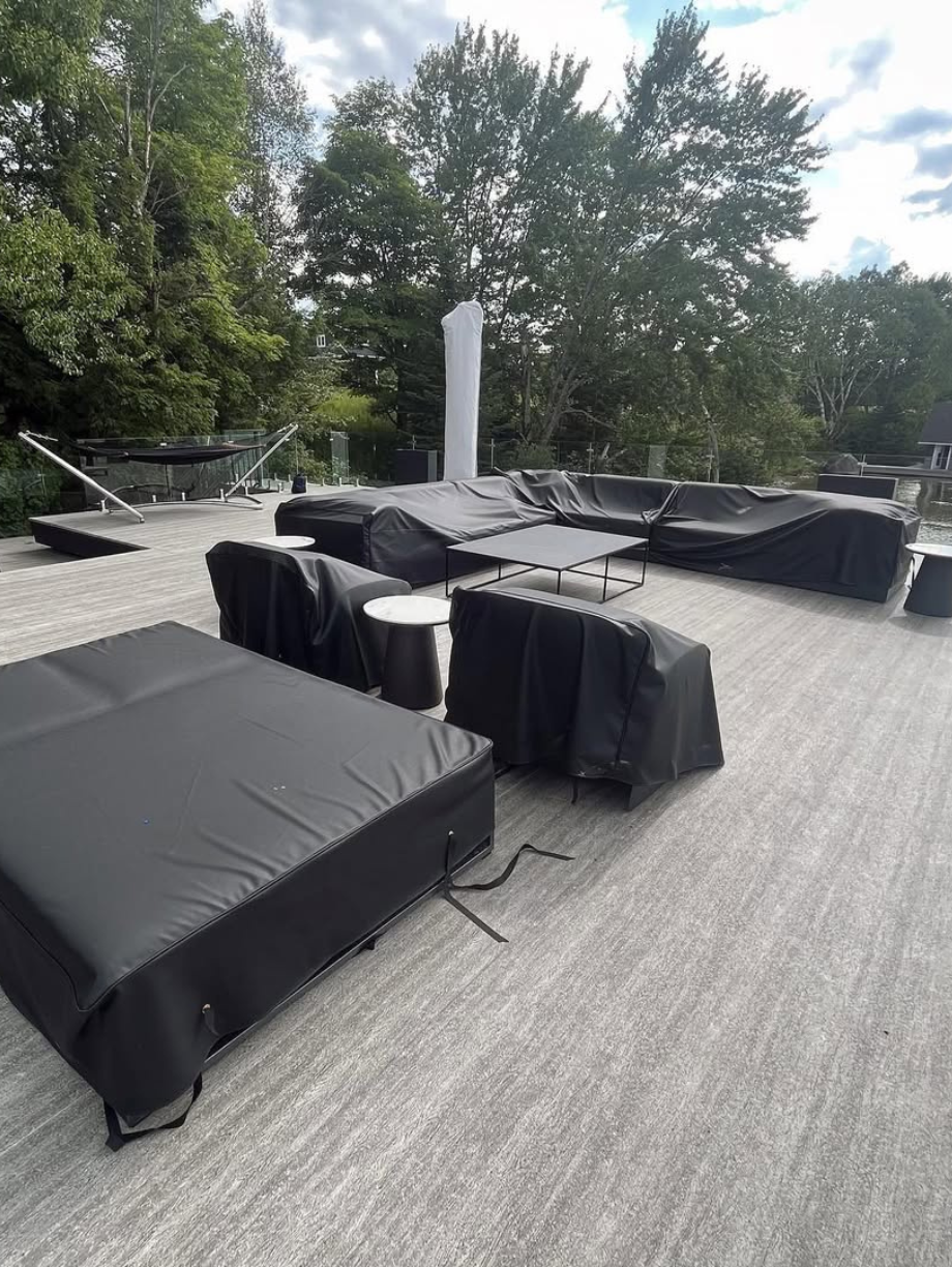 Outdoor patio furniture covered with protective black covers on deck